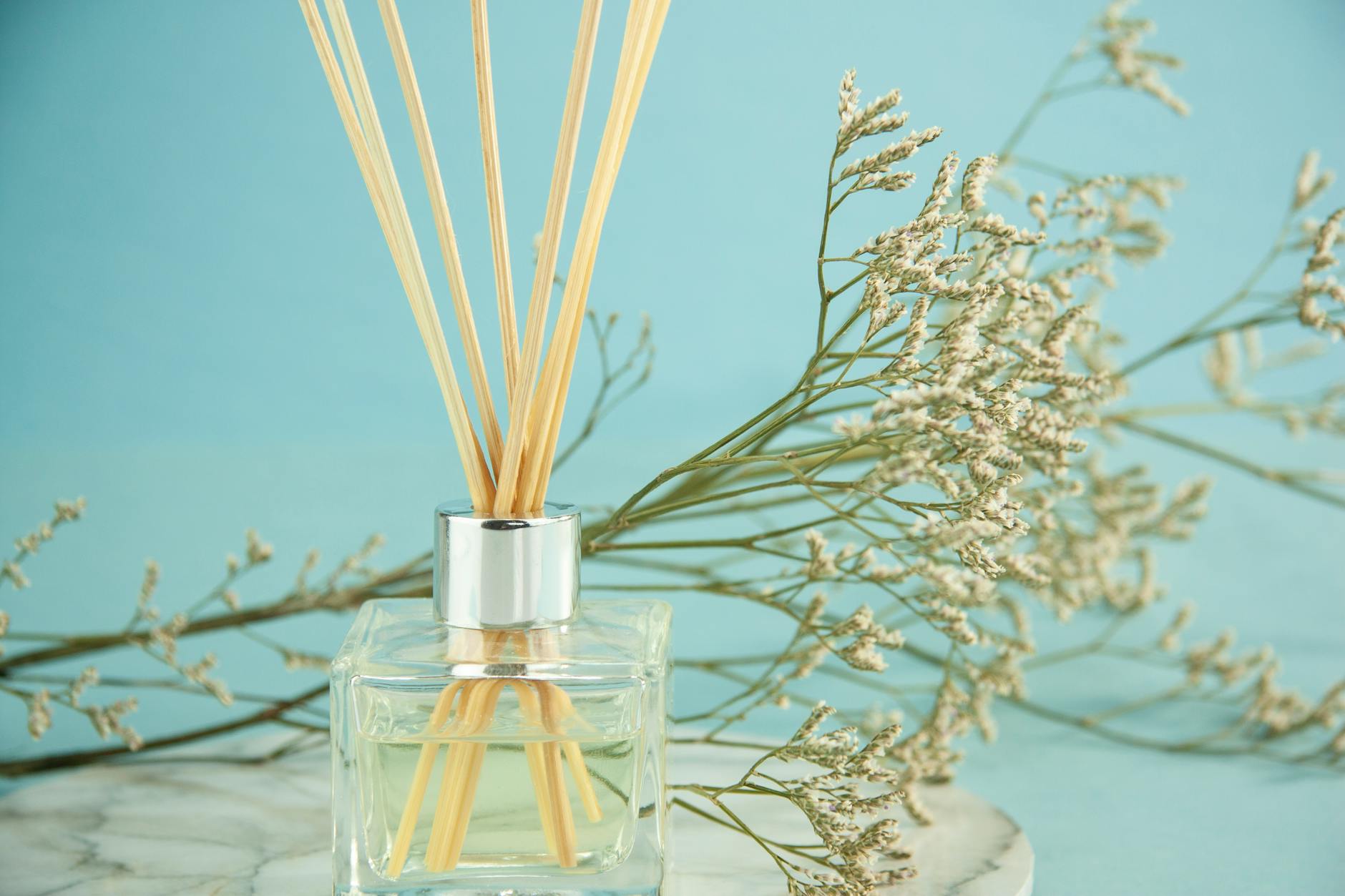 bottle of essential oil with sticks near blooming branches